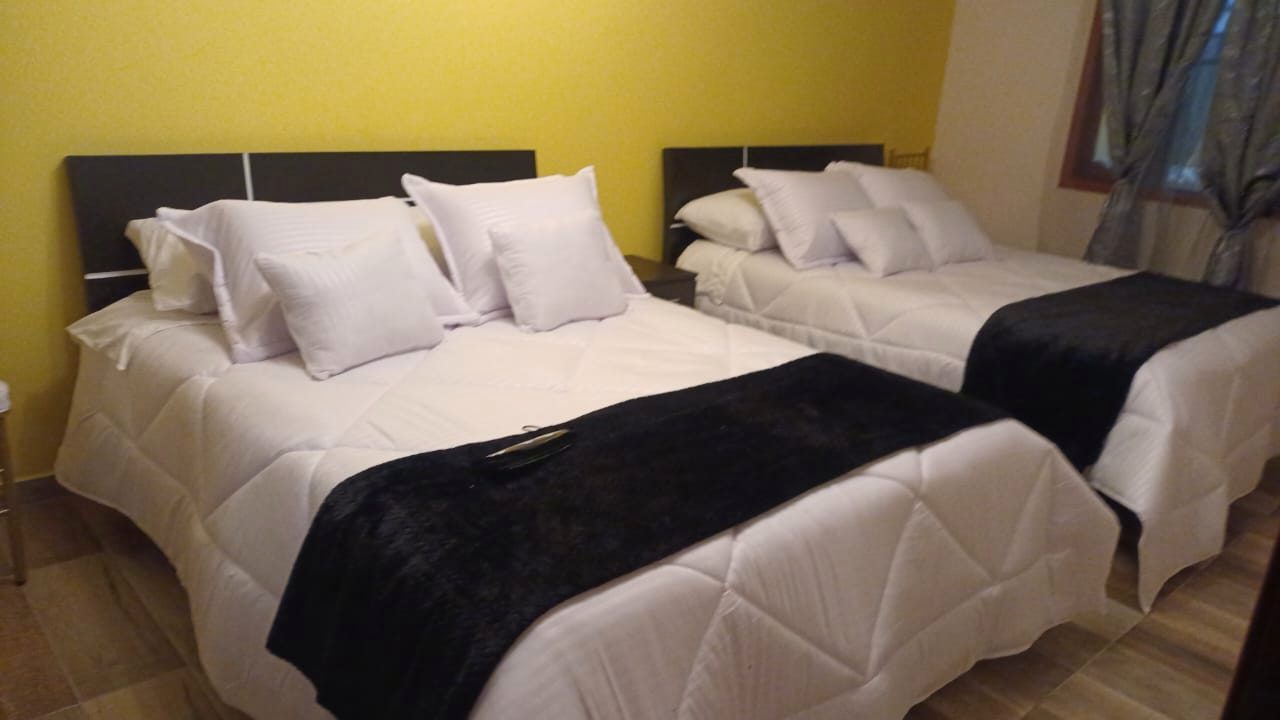 Habitación con camas dobles y pared amarilla