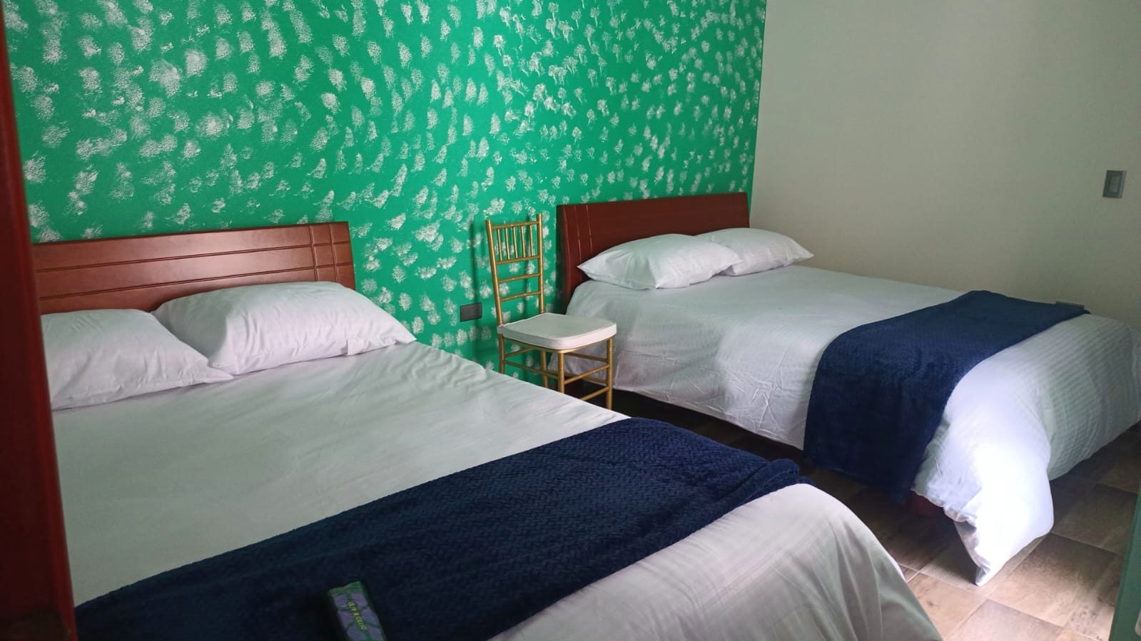 Habitación con pared verde y dos camas