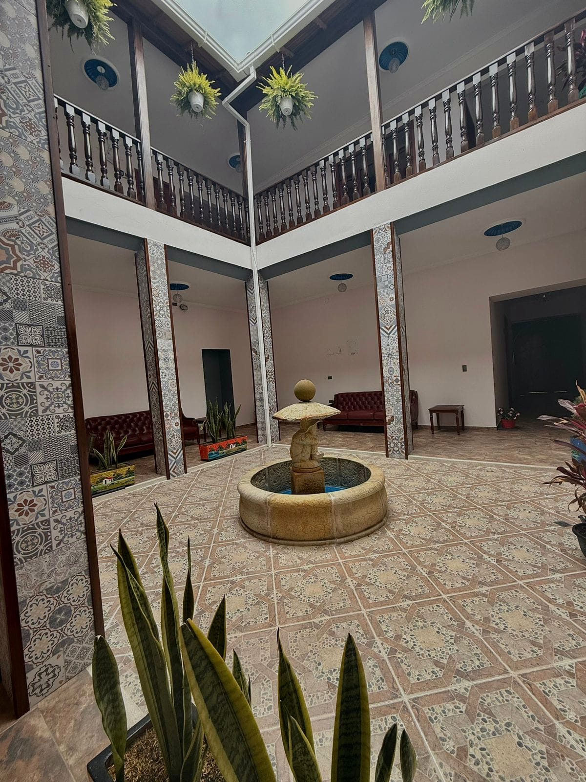 Patio central con fuente de piedra y balcones de madera
